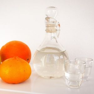 rakija u boci s dvije čaše i narančom